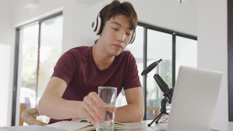 헤드폰을 착용 한 아시아 소년 은 가정 에서 오디오 캐스트 를 녹음 하기 위해 전문 마이크 로 말 하고 있다