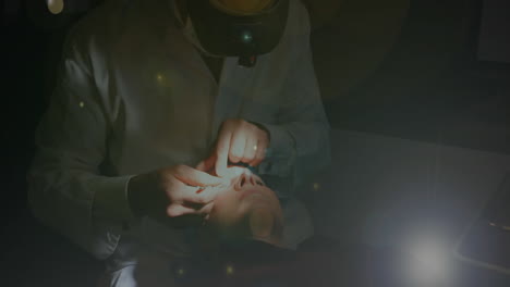 spots of light against male doctor operating eyes of female patient