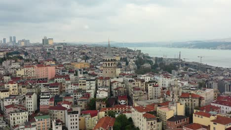 aerial drone circling galata tower in taksim istanbul turkey on a cloudy day overlooking old european residential buildings and the bosphorus river