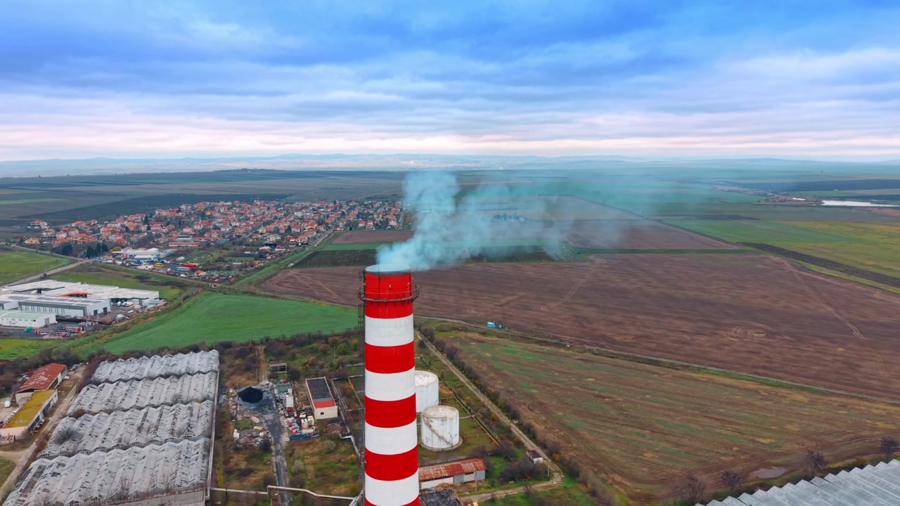 Fabbrica con camino rosso e bianco. Una vista dall'alto di un'area industriale che mostra un camino con fumo