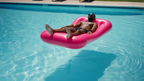 man relaxing on a pink float in a swimming pool