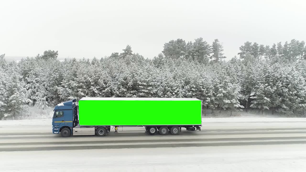 이한 겨울 풍경의 도로의 공중 풍경과 그 몸의 쪽에 크로마 키 녹색 장소를 가진 운전 트럭.