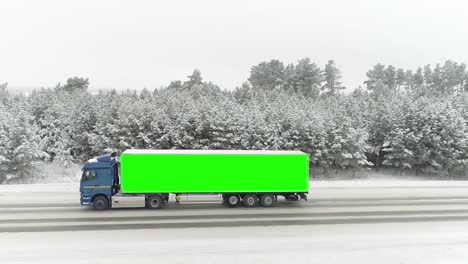 vista aérea de una carretera en un idílico paisaje de invierno y un camión de conducción con lugar verde clave de croma en el lado de su cuerpo. escena. concepto de publicidad y transporte