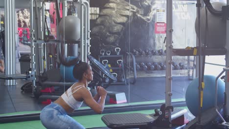 jumping squats performed by a female bodybuilder at the gym with her reflection in the background