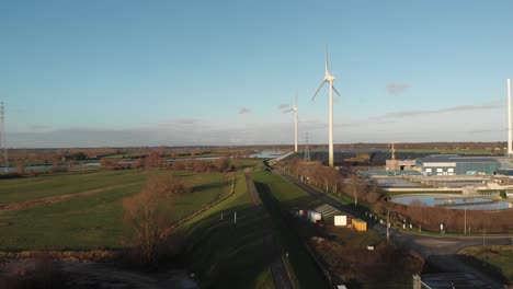 Auen-Und-Radweg-Auf-Einem-Deich-Entlang-Industriegebiet-Mit-Windrädern-Und-Kläranlage-Vor-Blauem-Himmel