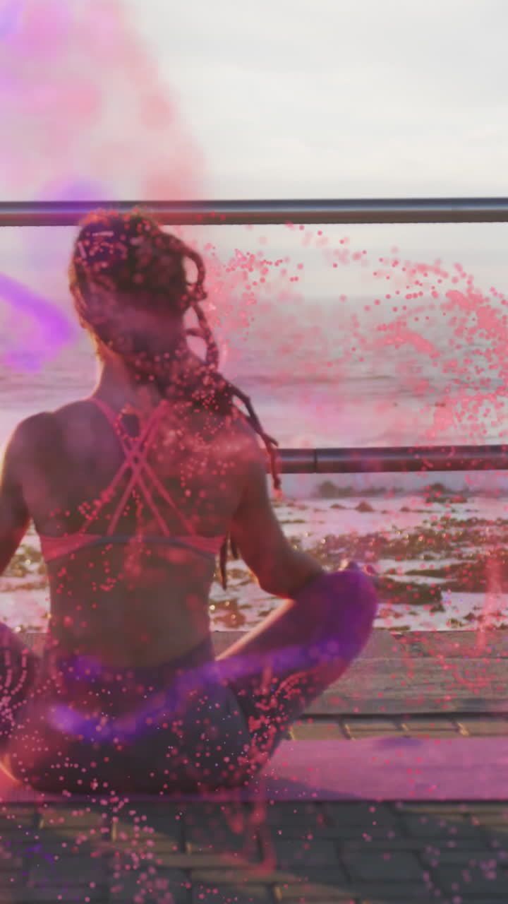 Animazione di macchie colorate su una donna birazziale che medita in riva al mare.