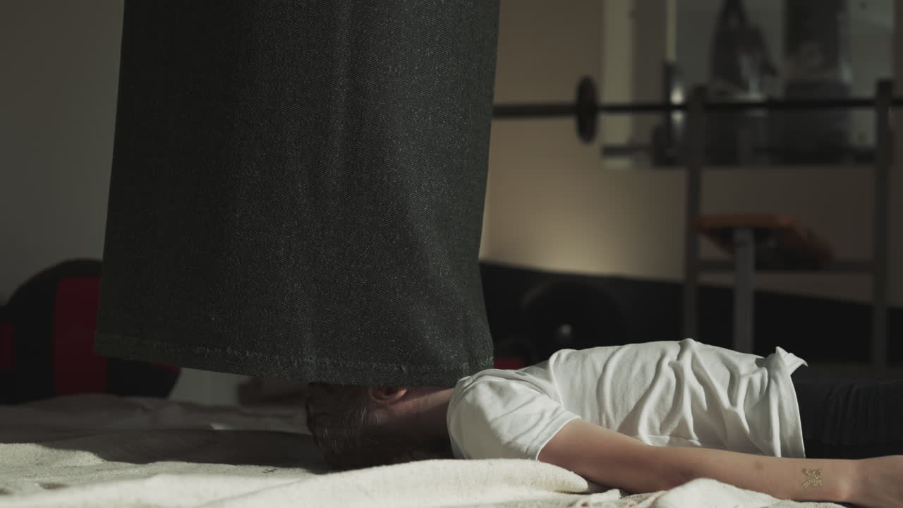 스포츠 센터에서 누워있는 아이 위에 돌을 던지는 주머니. 직물 케이싱의 가장자리는 무술 체육관에서 작은 소녀의 얼굴을 만니다. 느린 동작. 피곤한 아이는 바닥에 휴식을 취합니다.