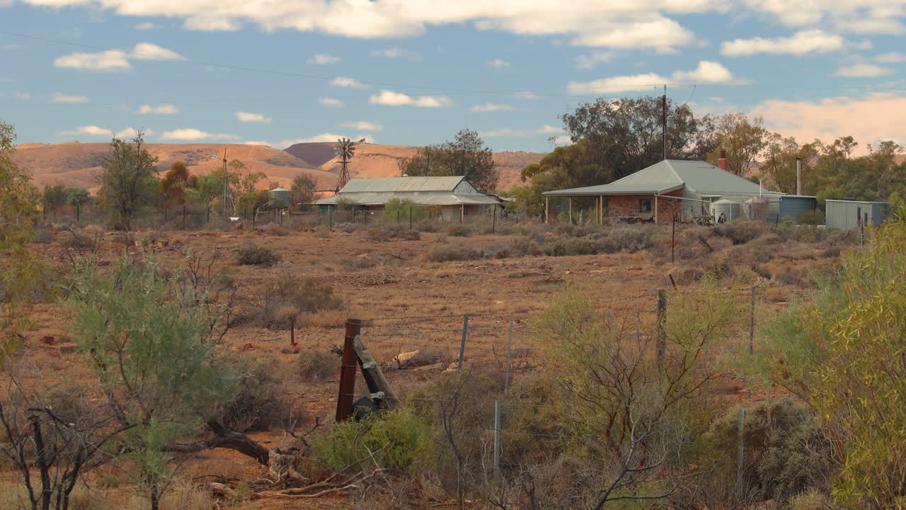 This video captures rustic buildings, a classic windmill, and the vast, arid Australian landscape under a wide-open sky. Perfect for conveying remote charm and heritage.