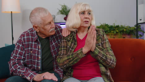 senior elderly family couple grandparents man woman pray with hope, making wish, begging apology