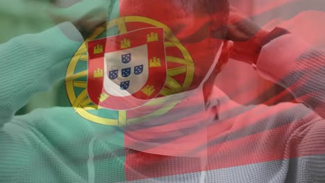 animation of flag of portugal waving over man wearing face mask during covid 19 pandemic