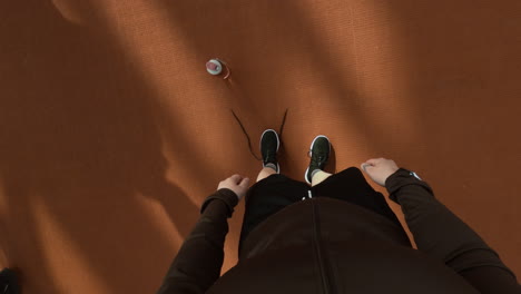pov shot of person tying shoelaces on running track before exercise