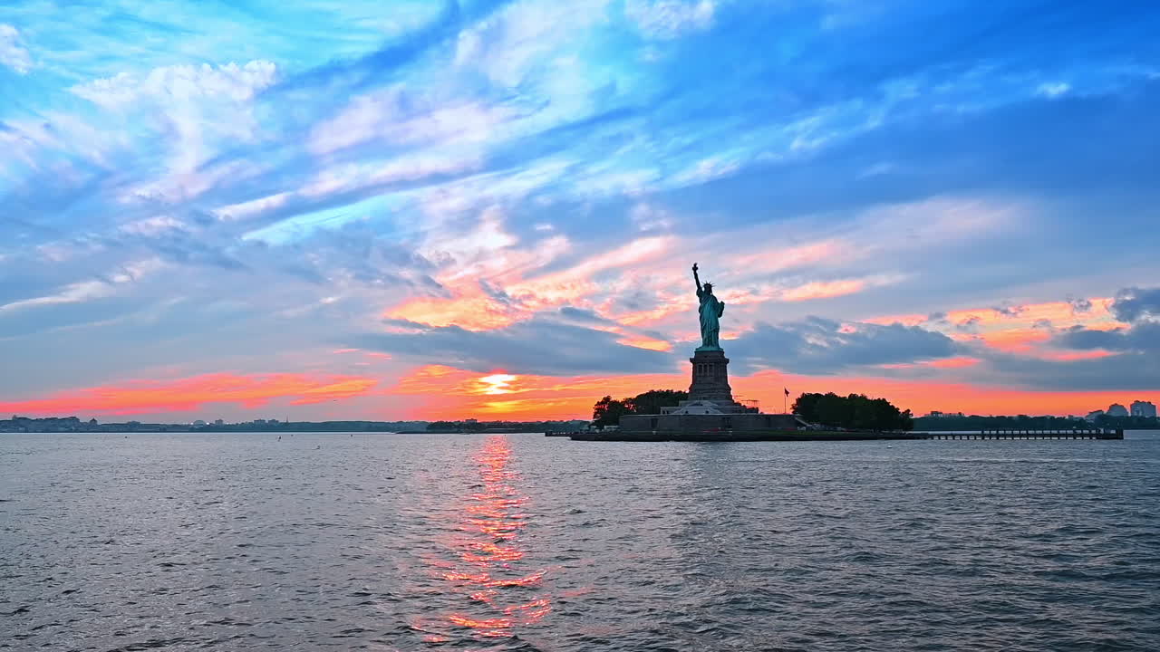 Statue of Liberty in New York at the backdrop of sky at sunset time. Famous American landmark from the waterscape. Low angle view