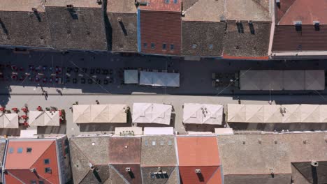 droner top-down shot of a touristic street with bar terraces and umbrellas in a european city