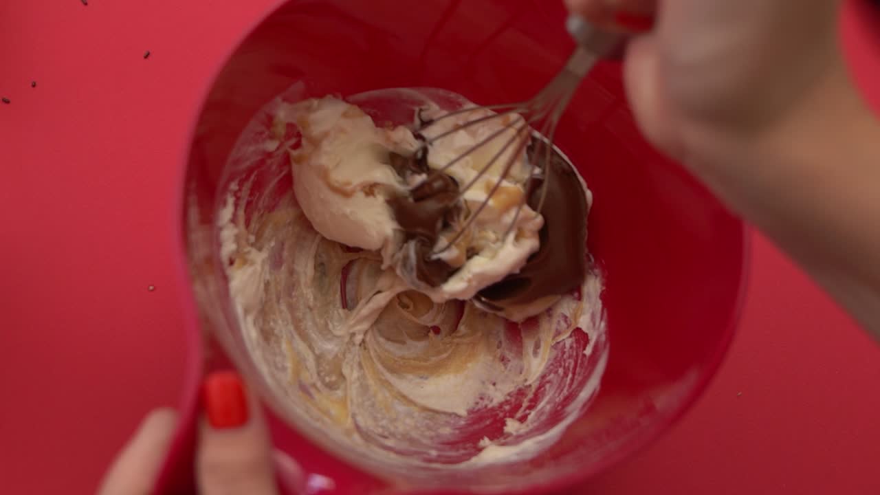 Laver hjemmelavet is, blander chokolade-, jordnøddesmør- og vaniljeis i en skål.