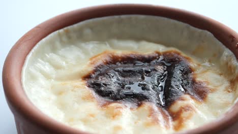 close up of a turkish milk pudding (sütlaç) in a clay pot