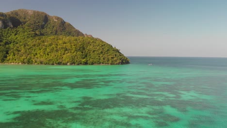 tonsai bay unspoilt exotic paradise harbouring fleet of small boats in ko phi phi don island, thailand - aerial fly-over shot