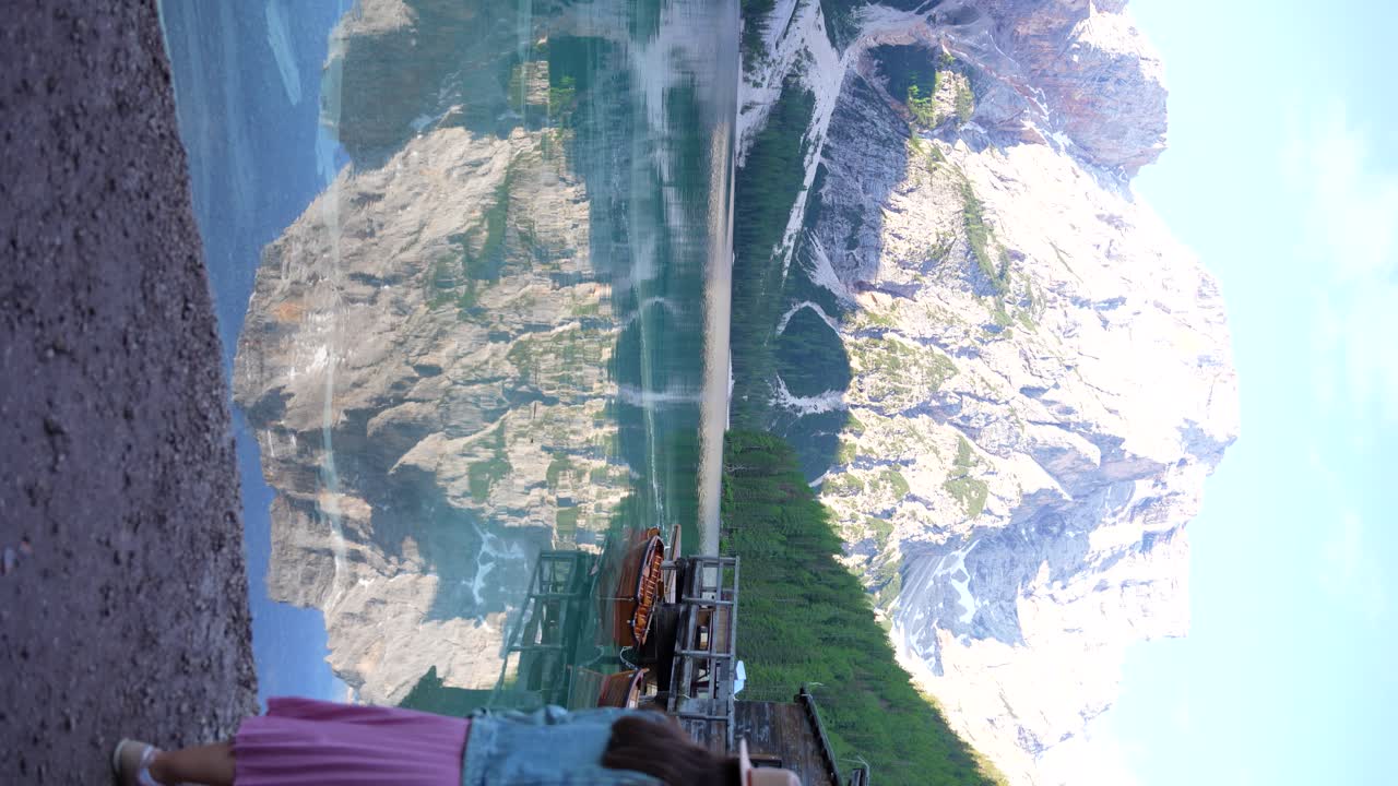 croda del becco se refleja en las aguas cristalinas del lago braies mientras la mujer pasa