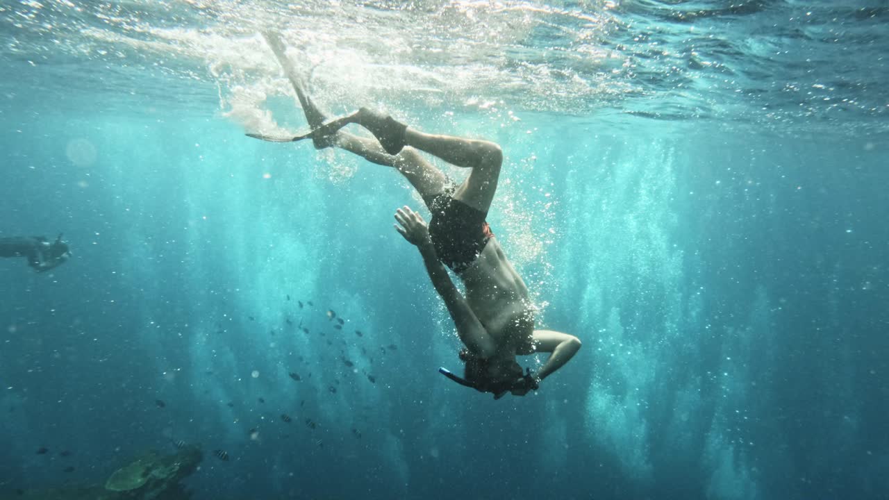 A freediver swims underwater near Tulamben, Bali, exploring the Liberty shipwreck