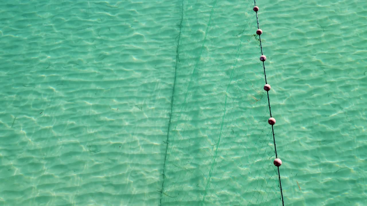 Fish Swimming Along Fishing Net in the Mediterranean Aegean Sea: Aerial View of a Traditional Trap in Thessaloniki's Crystal Clear Blue Waters