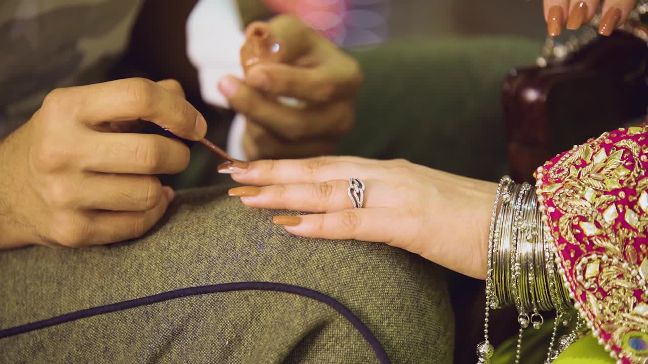 la esteticista está pintando las uñas de la novia asiática con esmalte de uñas.