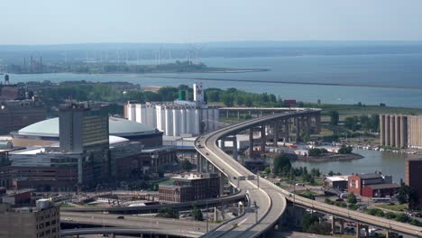 an aerial view of the city of buffalo, new york and its infrastructure of bridges and buildings beside lake erie with some wind turbines in the background