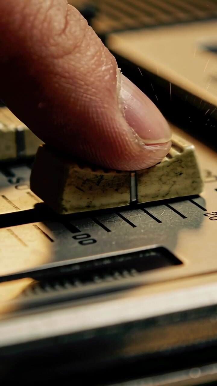 Video verticale: Punta del dito che preme e sposta il cappuccio beige usurato di un fader su una traccia della console per regolare il livello