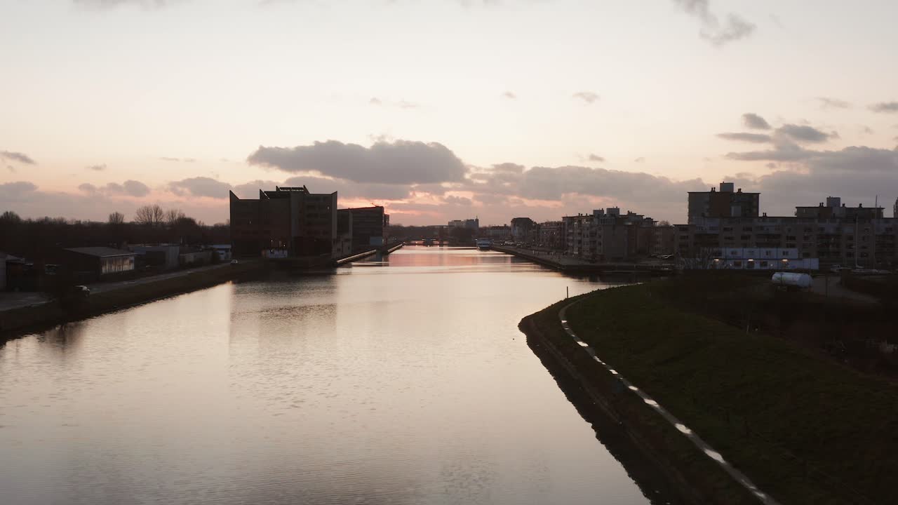 Drone flying over a canal towards the city showing the residential buildings and offices