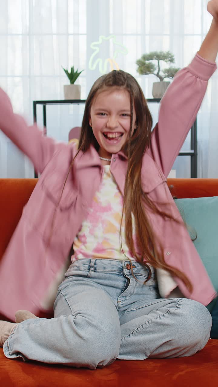 Happy girl child shouting celebrating win goal good news lottery luck victory watching tv at home
