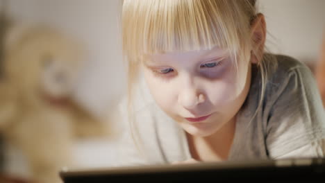 Porträt-Eines-Kindes,-Das-Ein-Tablet-Mit-Einem-Schlafzimmer-Genießt,-Liegt-Abends-Auf-Seinem-Bett