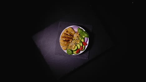 vista de pájaro de un plato giratorio de carne cocida con un lado de verduras frescas, pepino, cebolla, tomate y adornado con albahaca, cortado, con espacio para copiar