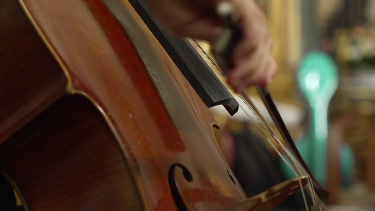 Detailed close-up of a cello being played with a bow in an ornate setting