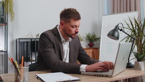 bored sleepy business man worker working on laptop computer, yawning, falling asleep at office