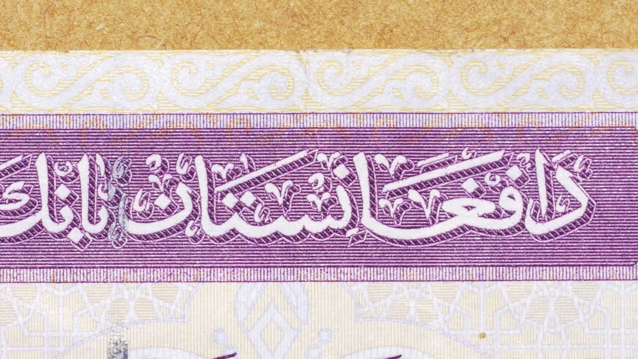 Macro pan across “Da Afghanistan Bank” in Pashto script with guilloche detail on an afghani note