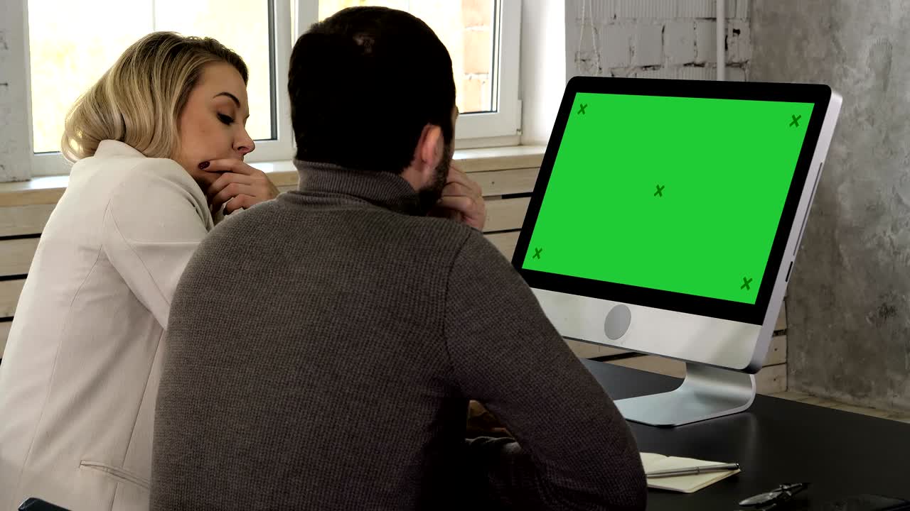 hombres de negocios que trabajan juntos comparando información de una computadora de escritorio en la oficina. pantalla verde muestra una maqueta