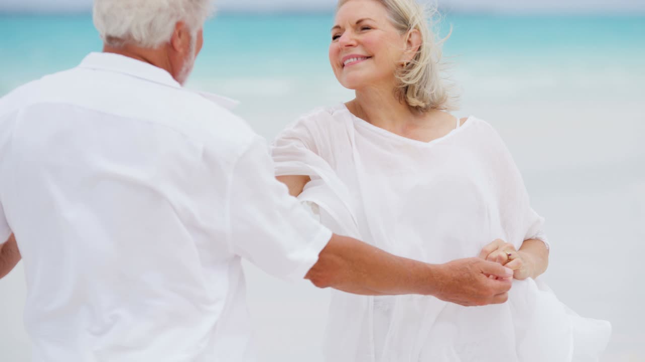 은퇴 한 백인 부부 가 열대 해변 에서 맨발 로 춤추고 있다