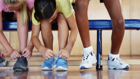 girls tying shoe laces in basketball court