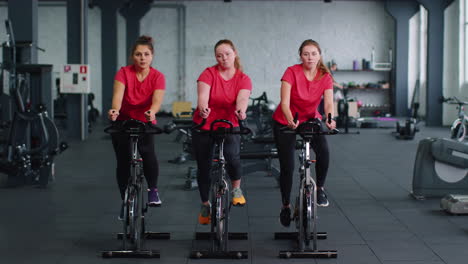 Un-Grupo-De-Chicas-Realiza-Una-Rutina-Cardiovascular-De-Entrenamiento-Aeróbico-En-Simuladores-De-Bicicletas,-Entrenamiento-En-Bicicleta.