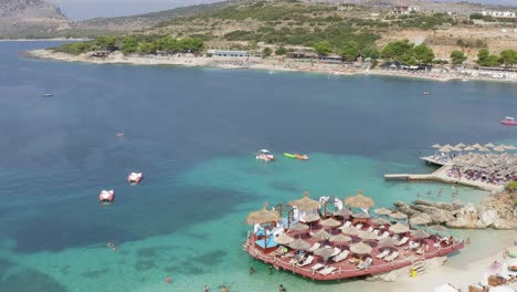 ksamil albania riviera summer on mediterranean ocean with straw umbrellas and lounge chairs, drone