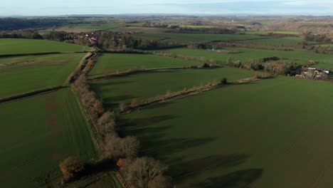 Drone-tilt-up-reveal-of-green-fields-at-high-altitude-over-gentle-rolling-hills-in-north-yorkshire-countryside-in-England-and-blue-skies-with-some-cloud