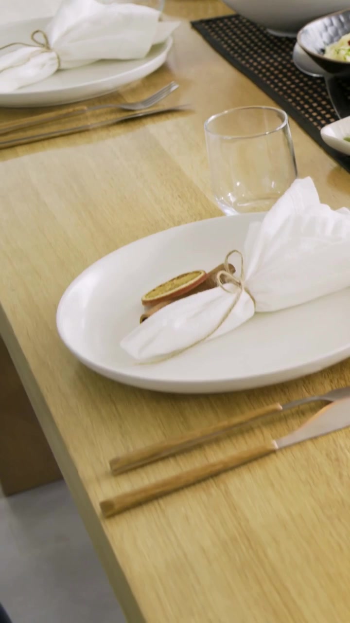 Vertical video: Panning camera revealing dining table in home, preparing meal with salad, napkins
