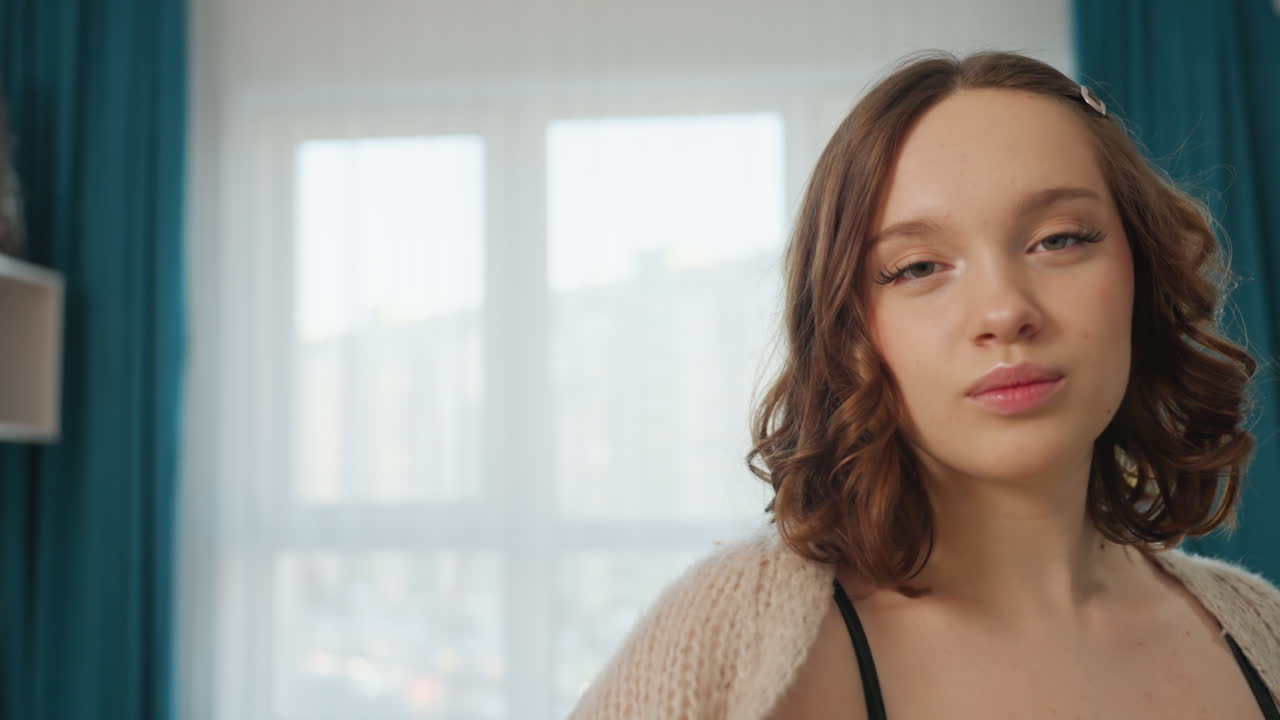 Thoughtful Woman Gazing Through Large Window, Softhaired Woman Wearing Sweater Looking Out Apartment Window, Serene Caucasian Female In Cozy Clothing Reflects While Facing Brightly Lit Window