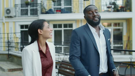 smiling mixed race business couple having pleasant conversation outdoors.