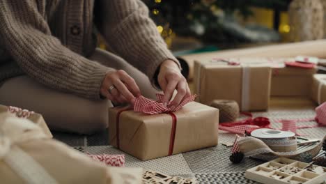 mujer caucásica irreconocible envolviendo regalos de navidad en el suelo.