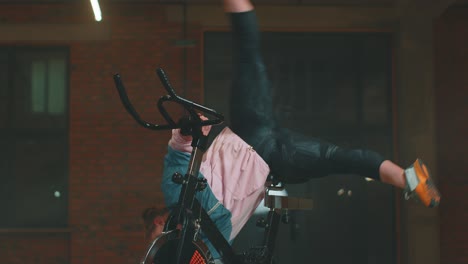 woman performing acrobatic balance on stationary bike in gym
