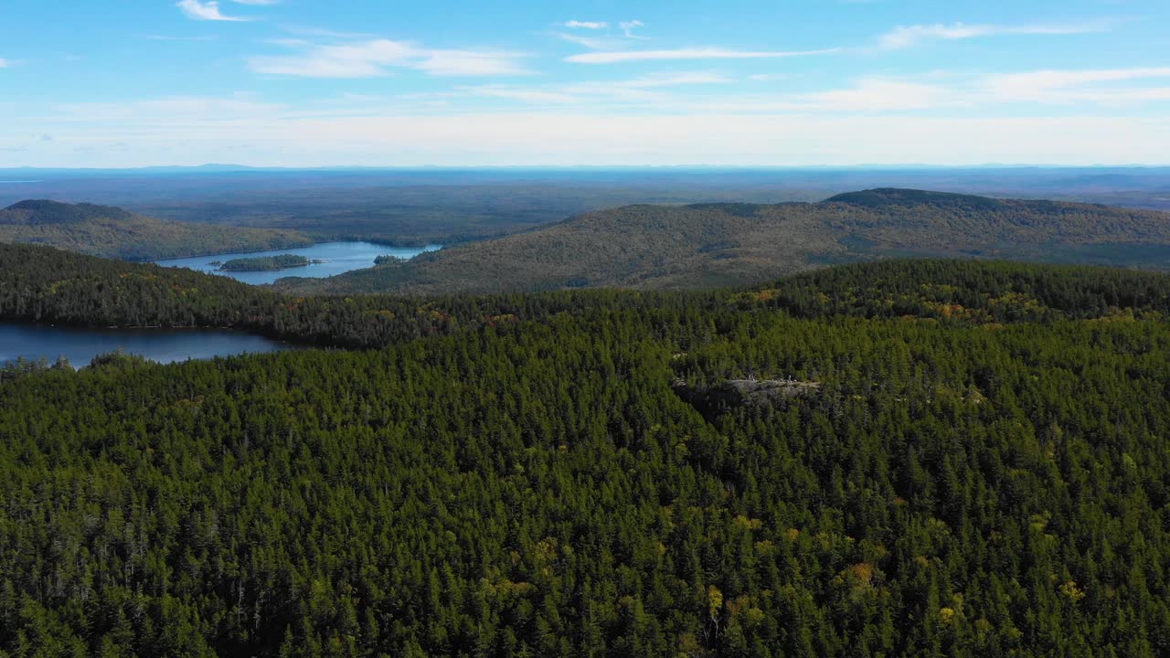메인 황야의 호수와 암석 노두가 있는 넓은 녹색 숲 위로 미끄러지는 공중 드론 샷