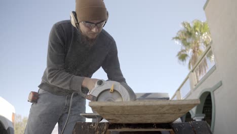 carpenter using electric circular saw outside on sunny day, low angle slow motion