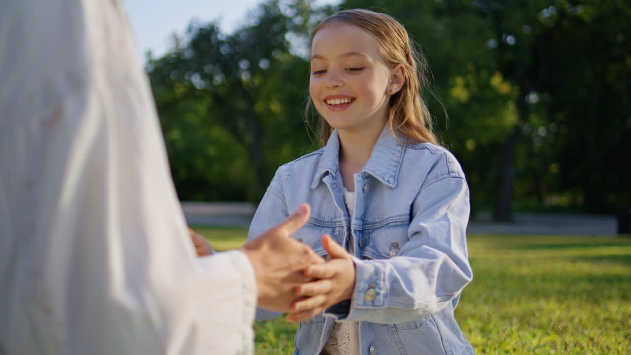 Small girl playing mother at sunny grass picnic closeup. Mom kid clapping hands