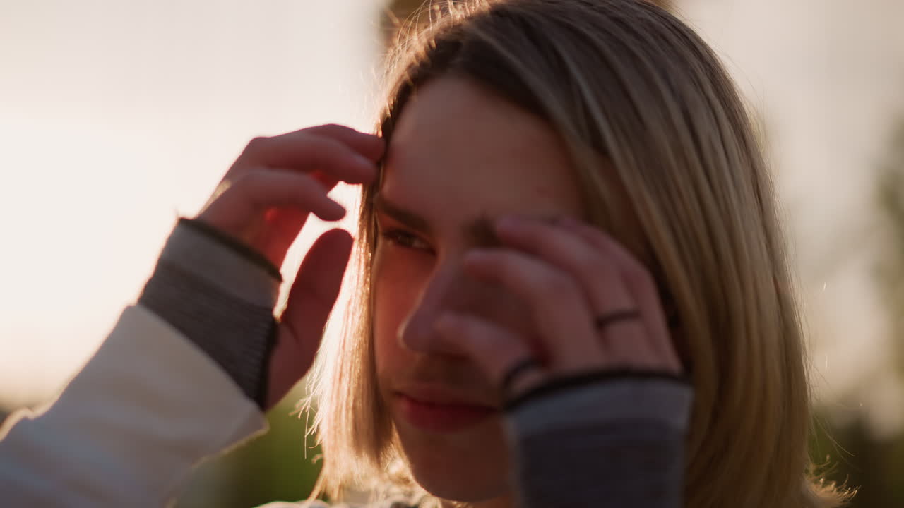 Tenåringsgitarist opplyst av kveldslys. Rolig utendørsscene med ung gitarist i skumringen. Fredfullt portrett som fanger en tenåringsmusiker midt i solnedgangens farger i en park