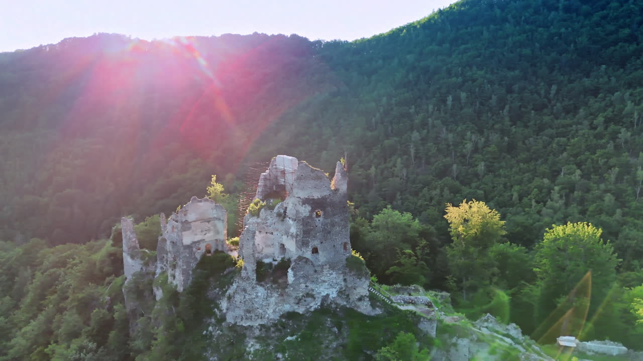 Flying around the ruins of the old castle standing on the top of the rock. Tatra mountains covered with woods surround the view