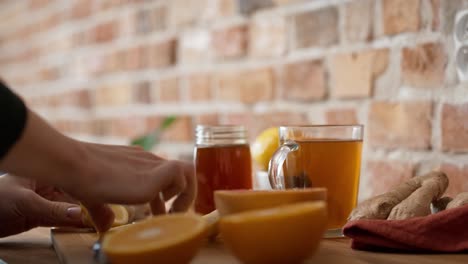 Hands-of-unrecognizable-woman-cutting-lemon-for-winter-tea